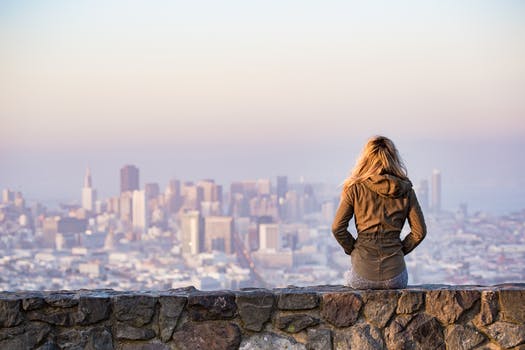 Woman sitting on the rock looking at a skyscraper